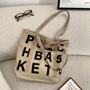 Macro detail of khaki canvas tote bag with black letter print and reinforced handles