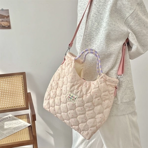Detailed view of pink quilted handbag with floral rabbit prints and woven handles