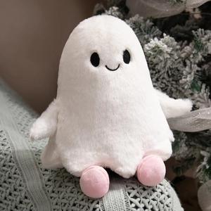 Detail of white ghost plush toy with soft fur and pink feet on a festive winter background