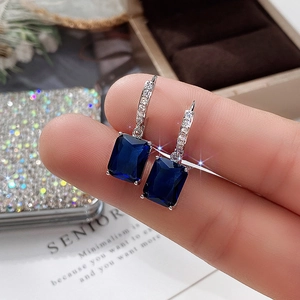 Close-up of deep blue rectangle zircon earrings held to show fine jewelry details