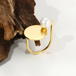 Detailed close-up of a vintage gold open ring with natural stone and pearl on dark wood