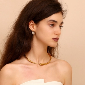 Elegant gold bow heart earrings and choker set worn by a model in a luxury style