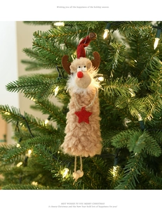 Detail of plush reindeer ornament hanging on a festive Christmas tree with warm lights