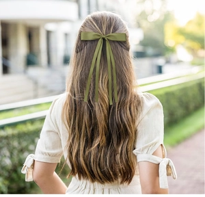 Detailed back view of long olive green ribbon bow hair clip on brown wavy hair