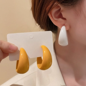 Close-up of minimalist chunky C-shape hoop earrings in yellow and white acrylic finish