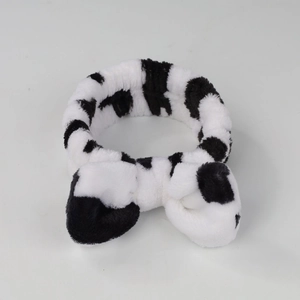 Macro detail of plush black and white cow print headband with soft coral fleece texture