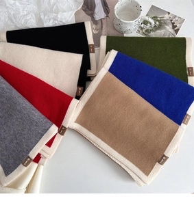 Flat lay of soft knit winter scarves in various colors with contrasting borders and labels