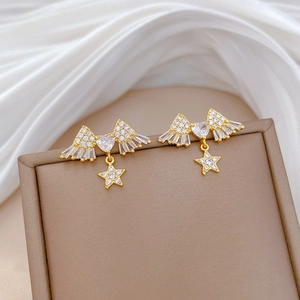 Detailed macro view of golden star and wing earrings with crystal zircon inlay
