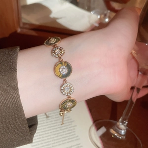 Detail eines 18K vergoldeten Tigerauge-Armbands mit Sonnenanhänger am Handgelenk