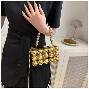 Detailansicht einer goldenen Perlen-Abendtasche, gehalten von einem Model in einem Raum