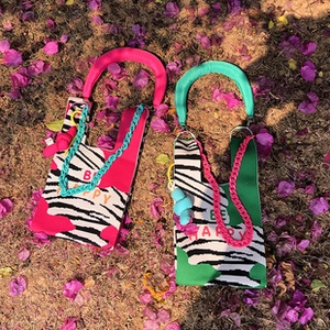 Detail of colorful knit handbags with zebra print and chunky chains on flowery grass