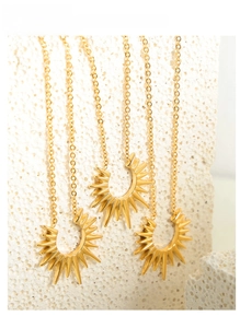 Macro shot of three gold plated titanium steel necklaces with radiant sunburst pendants