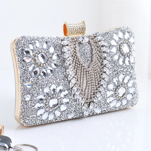 Detail of floral rhinestone patterns and luxury tassels on silver evening clutch bag
