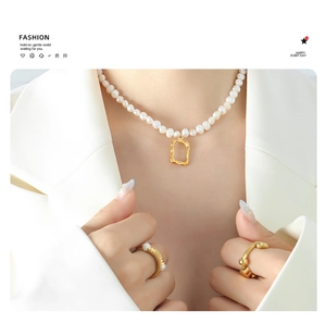 Detail of freshwater pearl necklace with irregular gold pendant and twisted gold ring