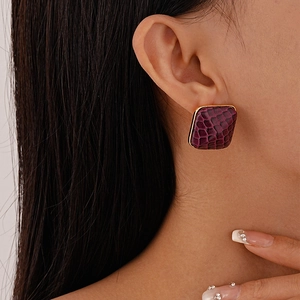 Close-up of square purple faux leather earrings with golden metal borders on a model
