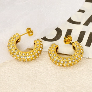 Détail de boucles d'oreilles créoles dorées avec pavé de zircons et fermoirs papillons