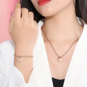 Vue détaillée de l'ensemble collier et bracelet à perles cœur en or rose sur modèle