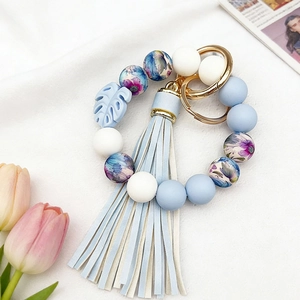 Close-up of floral beaded silicone keychain bracelet with blue leather tassel and gold ring
