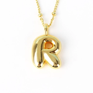 Macro shot of 3D balloon-style letter R pendant in polished gold finish for hip-hop necklace