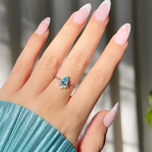Detail of water drop blue sapphire ring with micro-set diamonds on a model's hand