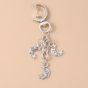 Retro silver alloy keychain with crescent moon and star charms on beige background