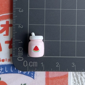Miniature pink dollhouse juice bottle with watermelon print on a centimeter scale pad