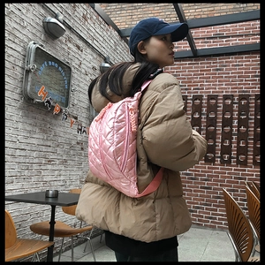 Detail of pink quilted waist bag with diamond stitching and adjustable shoulder strap