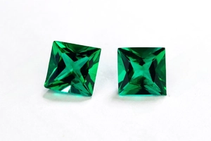 Macro shot of princess cut lab-created emerald gemstones with deep green facets