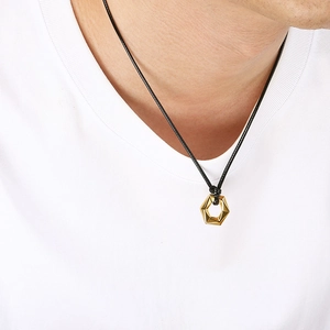 Men's minimalist gold hexagonal pendant necklace with black woven cord on white tee