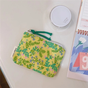 Close-up of a floral cotton coin purse with green zipper rope on a desk