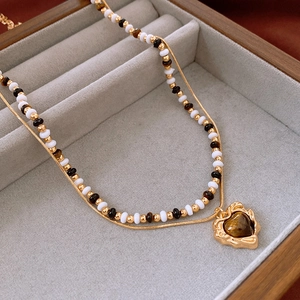 Detail of double-layer gold plated necklace with tiger eye heart pendant in jewelry box