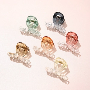 Top view of six small gradient acetate hair claws in assorted colors on pink background