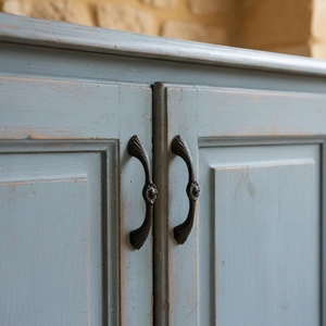 Vintage bronze cabinet handle with relief flower pattern on a rustic blue wooden drawer