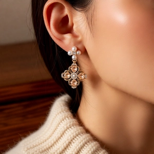 Macro detail of four-leaf clover drop earrings with champagne crystal and white pearl