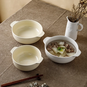 Set of three ceramic soup bowls with double handles and ribbed texture on brown tablecloth