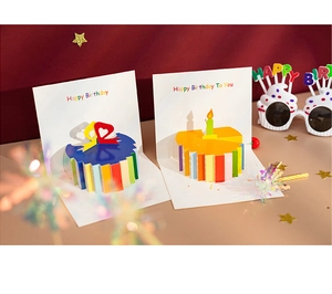 Detail of 3D pop-up birthday cards featuring blue and orange cake designs on red background