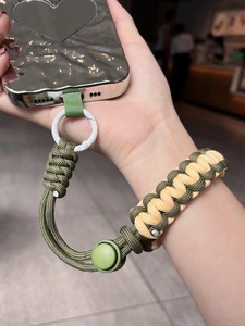 Adjustable woven wrist lanyard in army green and beige on a sleek silver phone case
