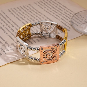 Detail of tricolor metal link bracelet with follow your heart engraving and crystals