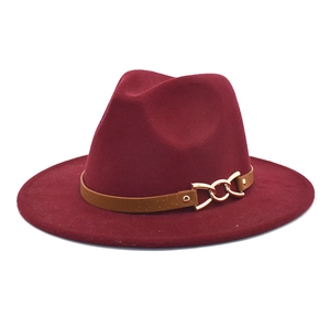 Detail of burgundy fedora hat featuring brown leather band and gold metal chain buckle