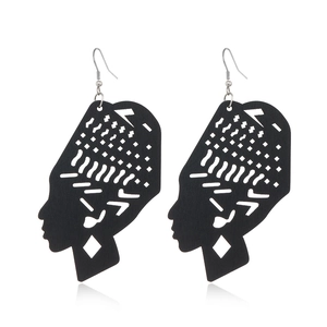 Detail of laser-cut black wooden earrings featuring African silhouette and geometric hollow patterns