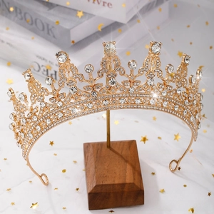 Detailed macro view of the crystal-studded gold crown on a rustic wooden display stand