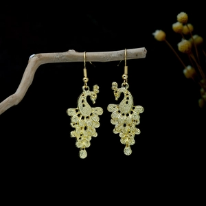 Detailed view of golden cloisonne peacock earrings with intricate hollow carvings