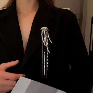 Detail of a jellyfish brooch with crystal tassels and white pearls on a black suit blazer