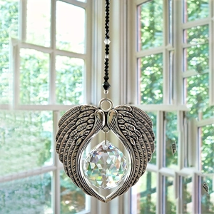 Close-up of crystal suncatcher with angel wings hanging by a window with natural light