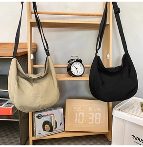 Detailed display of black and khaki nylon dumpling messenger bags on a wooden stand