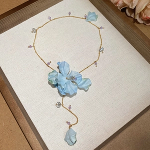 Detail of fabric flower pendant necklace with crystal beads and long tassel design