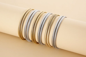 Détail de chaînes à chevrons plates dorées et argentées sur un support à bijoux beige