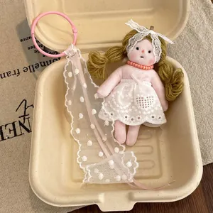 Detail of floral doll plush keychain with white lace ribbon in a gift box packaging