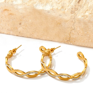 Golden C-shaped twist hoop earrings with inlaid zircons on a natural stone background