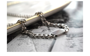 Macro shot of silver Cuban chain bracelet with a blank rectangular metal tag pendant